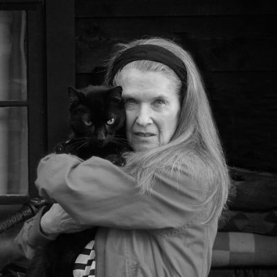 Anne Howell writer in her home with her black cat Jimmy